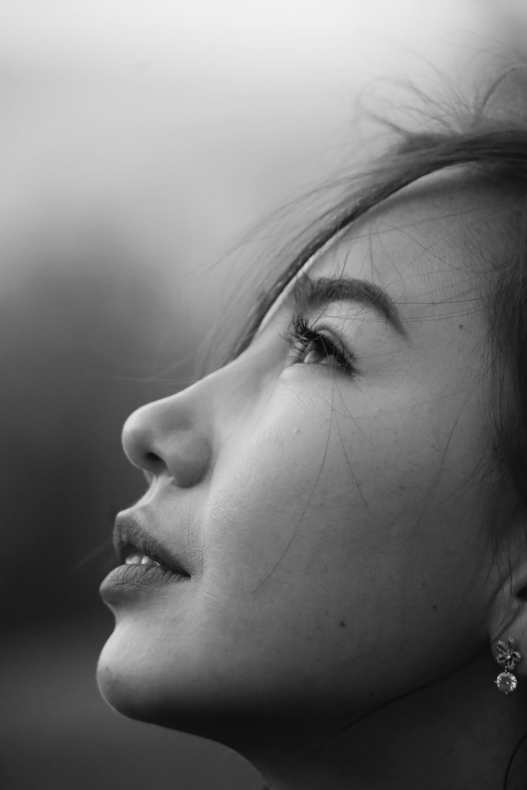 Close-up black and white profile portrait of a woman looking upwards, conveying serenity.